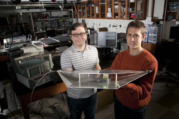 Deux étudiants en génie électrique de l'université Duke, Alexander Katko (à gauche) et Allen Hawkes, montrent un guide d'onde contenant une seule cellule en métamatériaux, qui fournit assez d'énergie pour alimenter une Led verte.